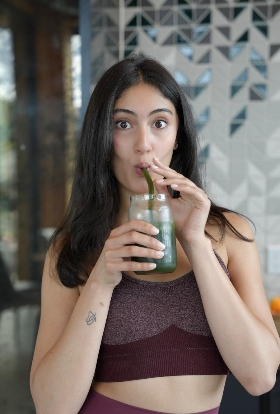 A woman holding a glass of the mixed green drink